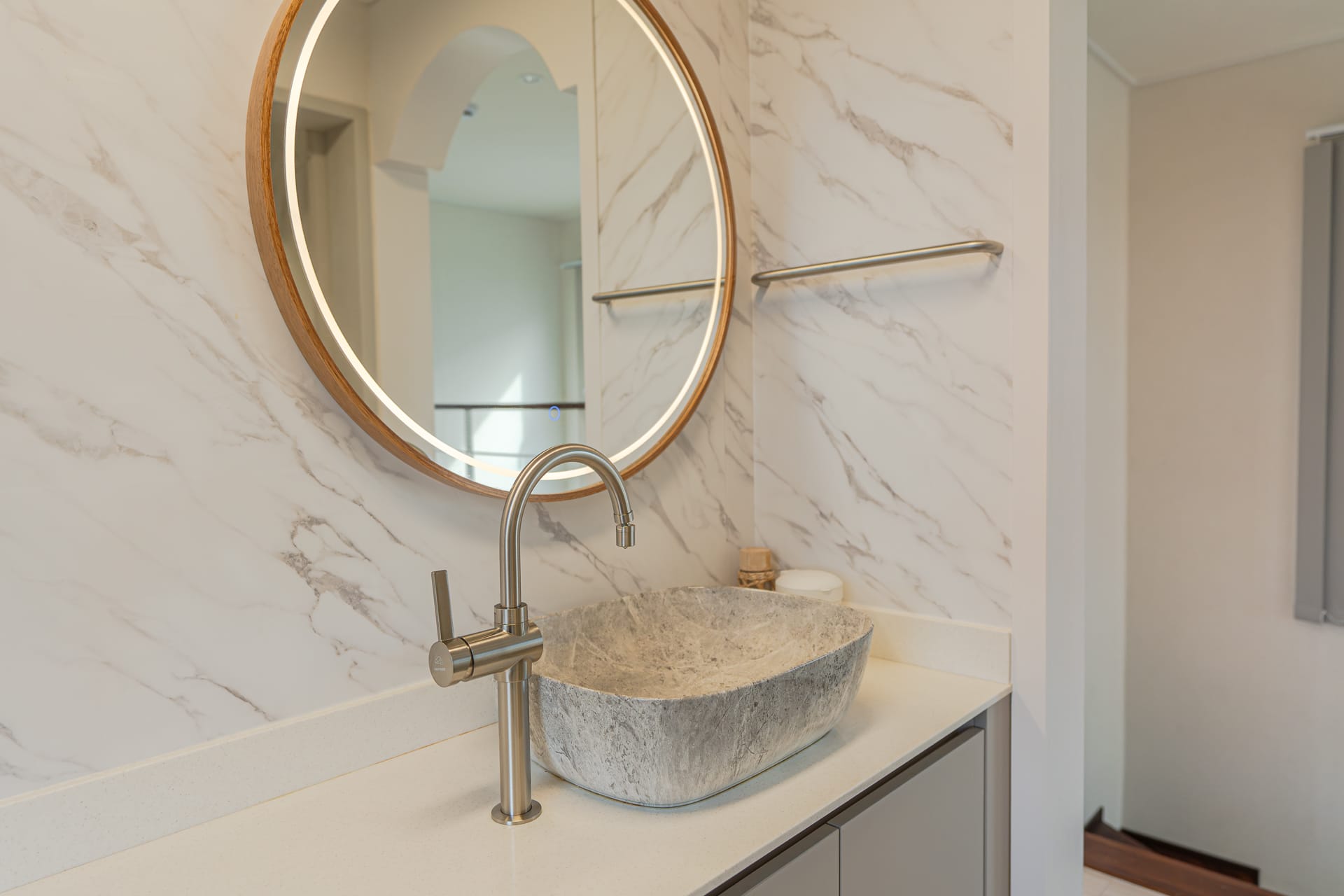 Bathroom with marble walls, a stone vessel basin and round mirror
