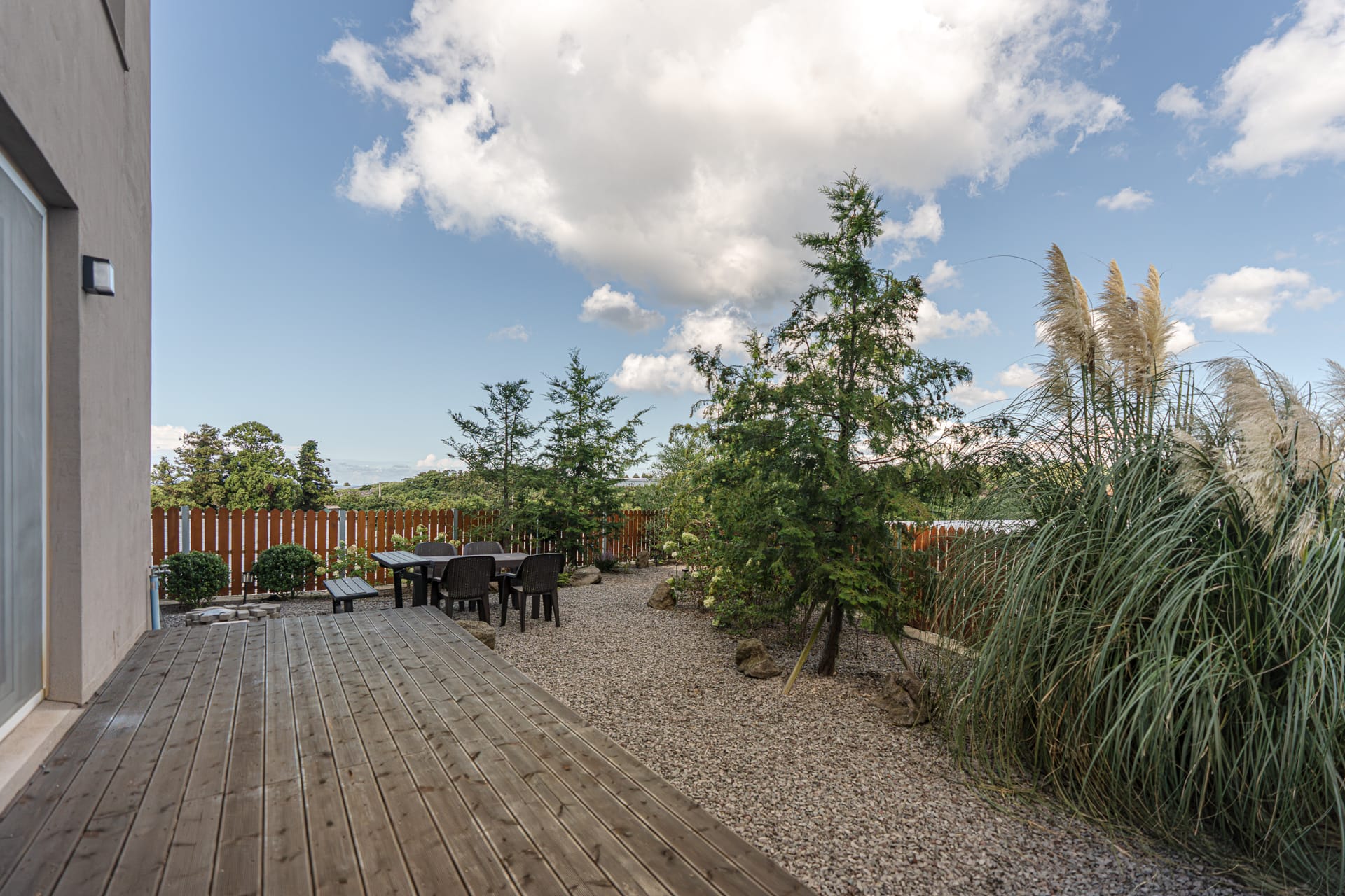 Timber terrace deck opening onto a gravel garden with pampas grass